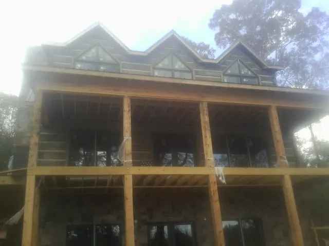 Dormers and porch framing on a large log home under construction — Roof Coating work by our crew in Garfield